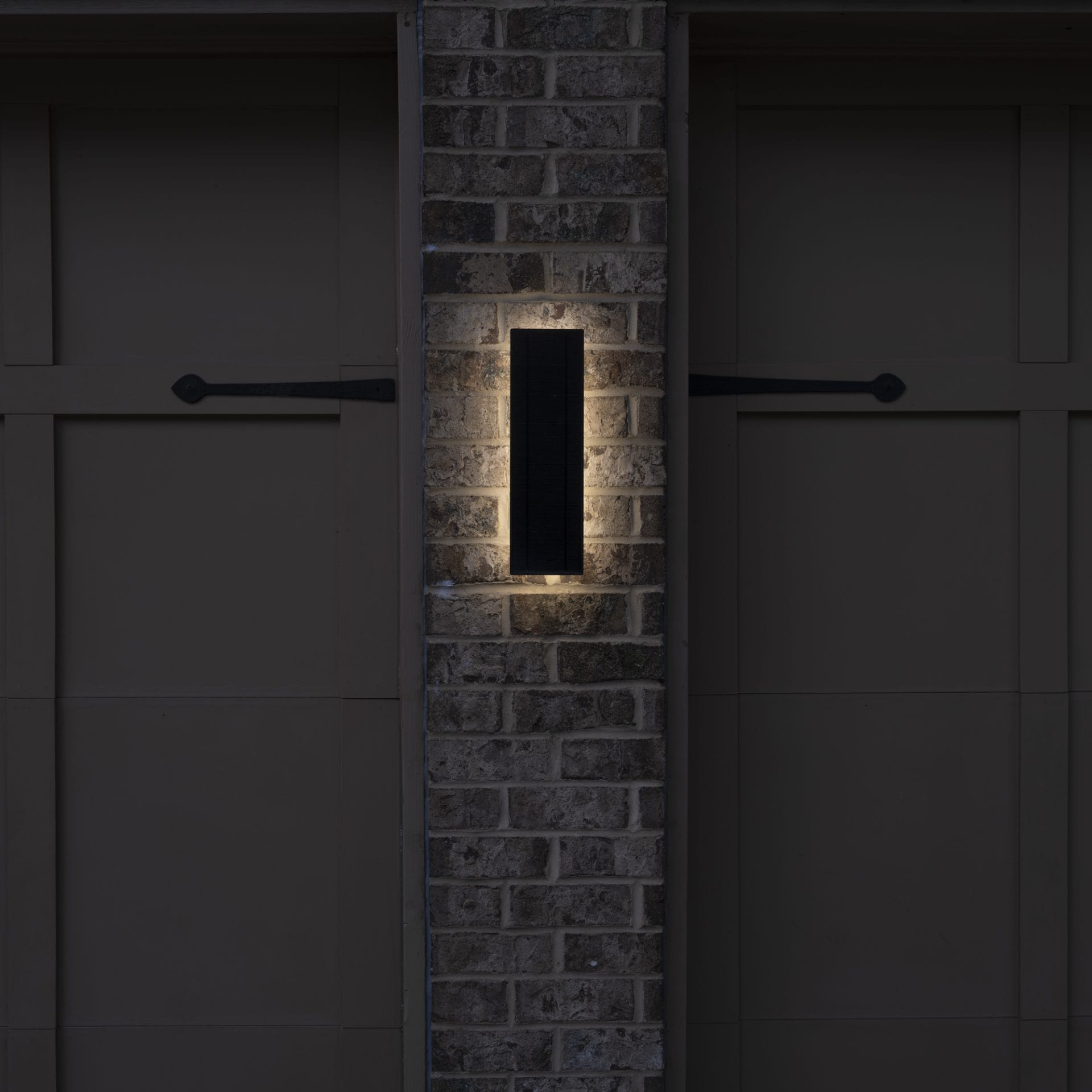 Slim vertical solar LED wall light with backlit halo glow at night