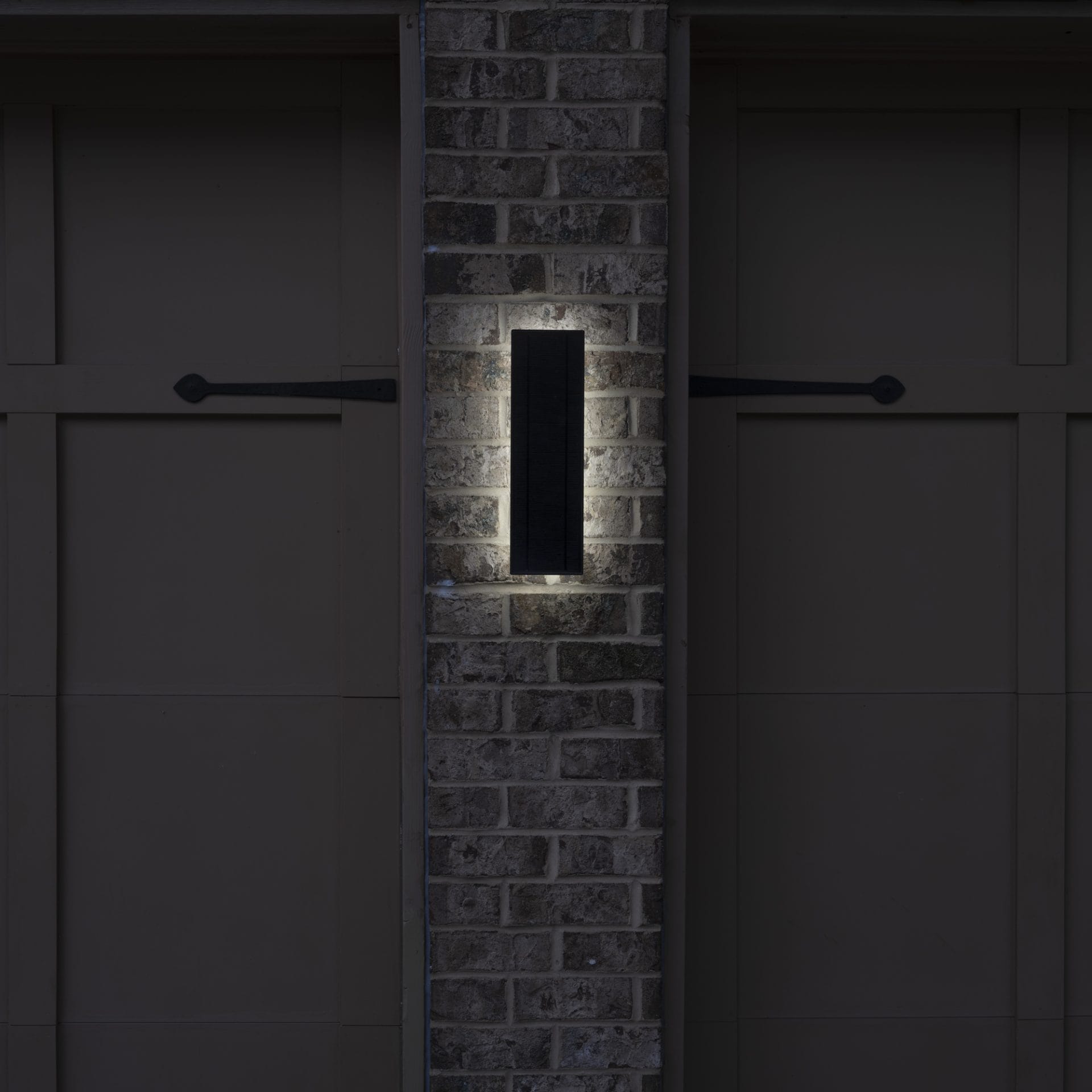 Slim vertical solar LED wall light with backlit halo glow at night